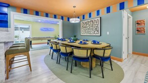 A dining area with a round table, chairs, and a chandelier. - Backyard Oasis Pool Hot Tub Putt Putt Bar (Largo)