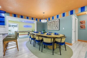 A dining area with a round table, chairs, and a chandelier. - Backyard Oasis Pool Hot Tub Putt Putt Bar (Largo)