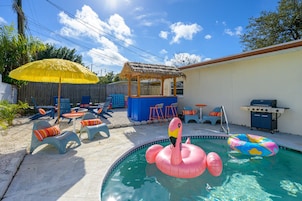 Patio con piscina, flotador de flamenco inflable y mobiliario exterior.
