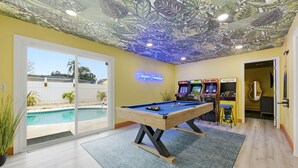 A pool table in a room with arcade games and a neon sign. - Backyard Oasis Pool Hot Tub Putt Putt Bar (Largo)