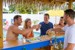 A group of people toasting at a bar with a pool in the background. - Backyard Oasis Pool Hot Tub Putt Putt Bar (Largo)