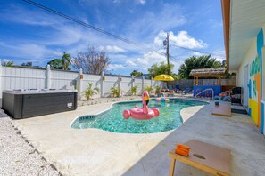 Una piscina con hidromasaje, sillas de descanso y una palapa.