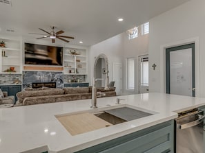 A modern kitchen with a central island, built-in appliances, and a large window. - House at the Refuge - Relax Take in Nature (Medicine Park)