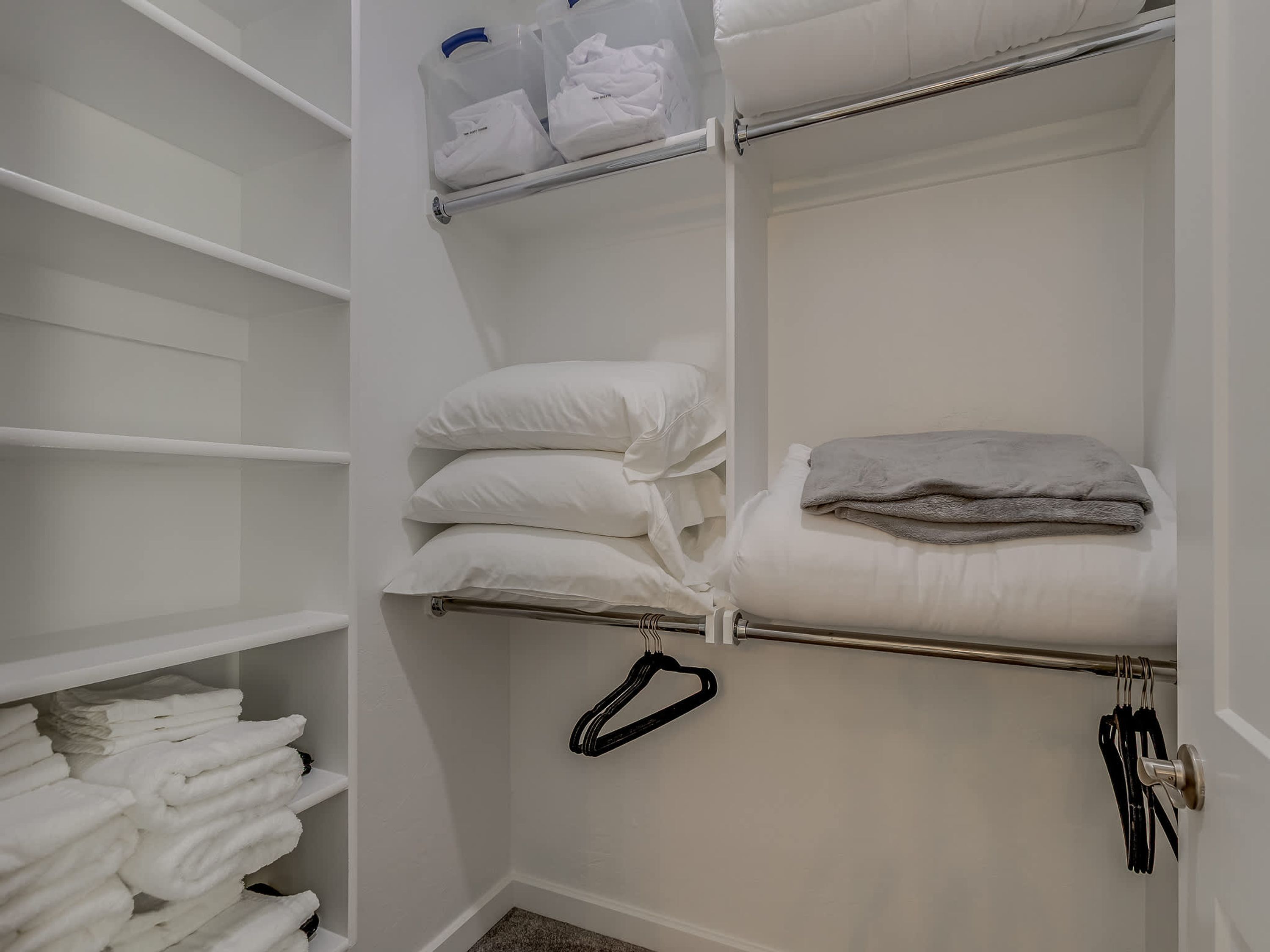Un armario con estantes, una barra para colgar ropa y una manta doblada.