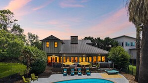 Una casa con piscina, mobiliario exterior y un patio bien iluminado.