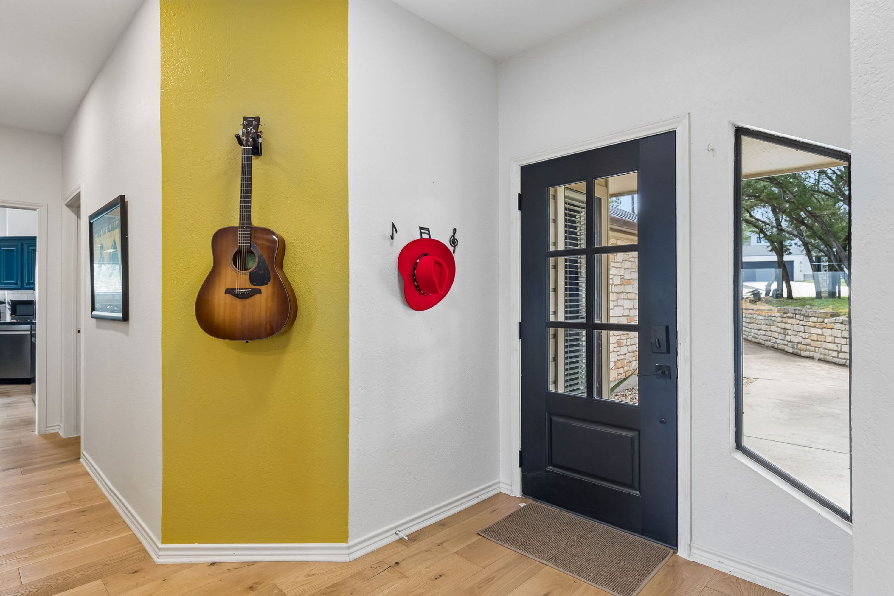 A hallway with a yellow wall, a black door, and a red hat hanging on the wall.