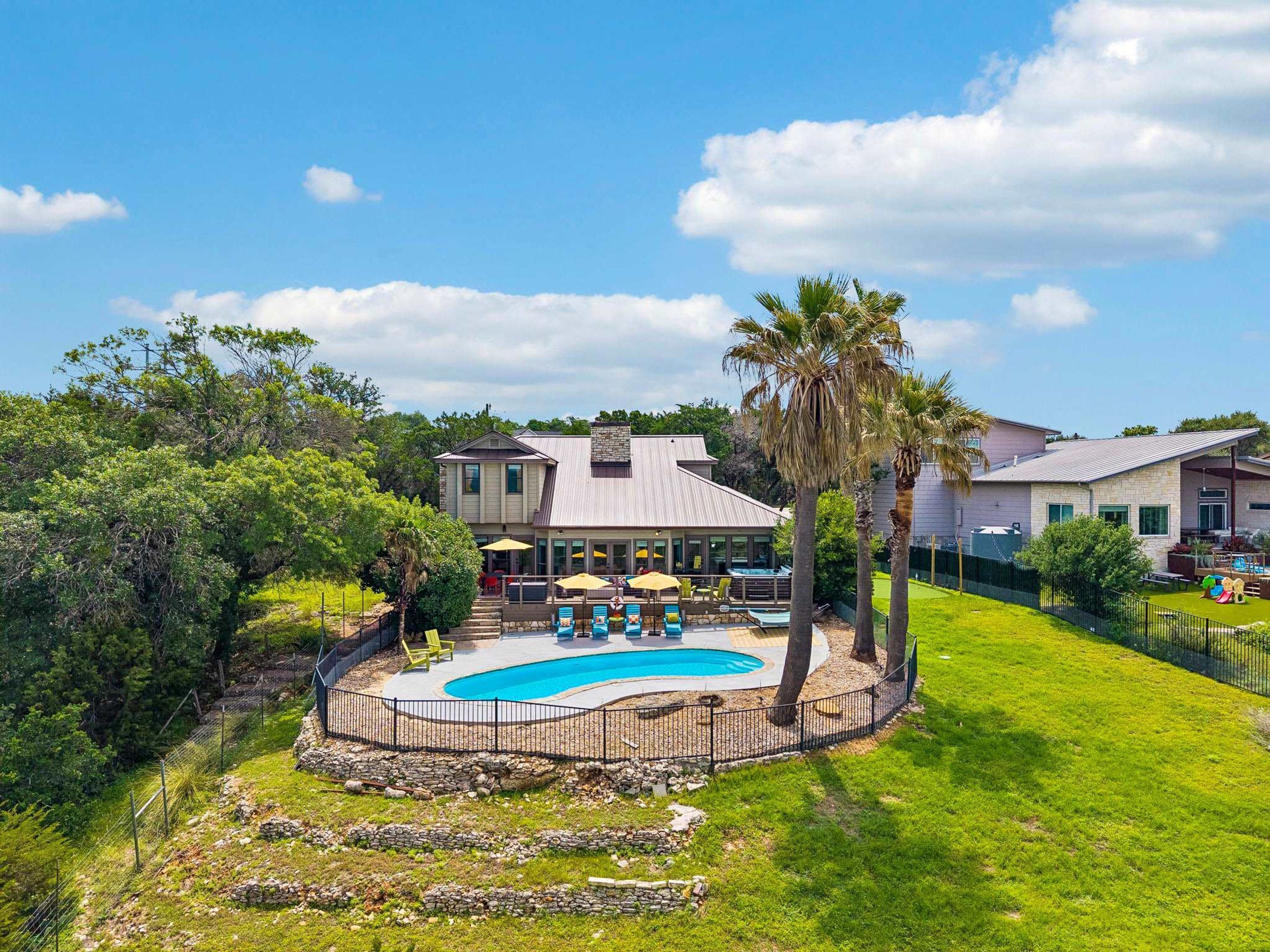 A residential property with a swimming pool, a covered patio, and a fenced yard.