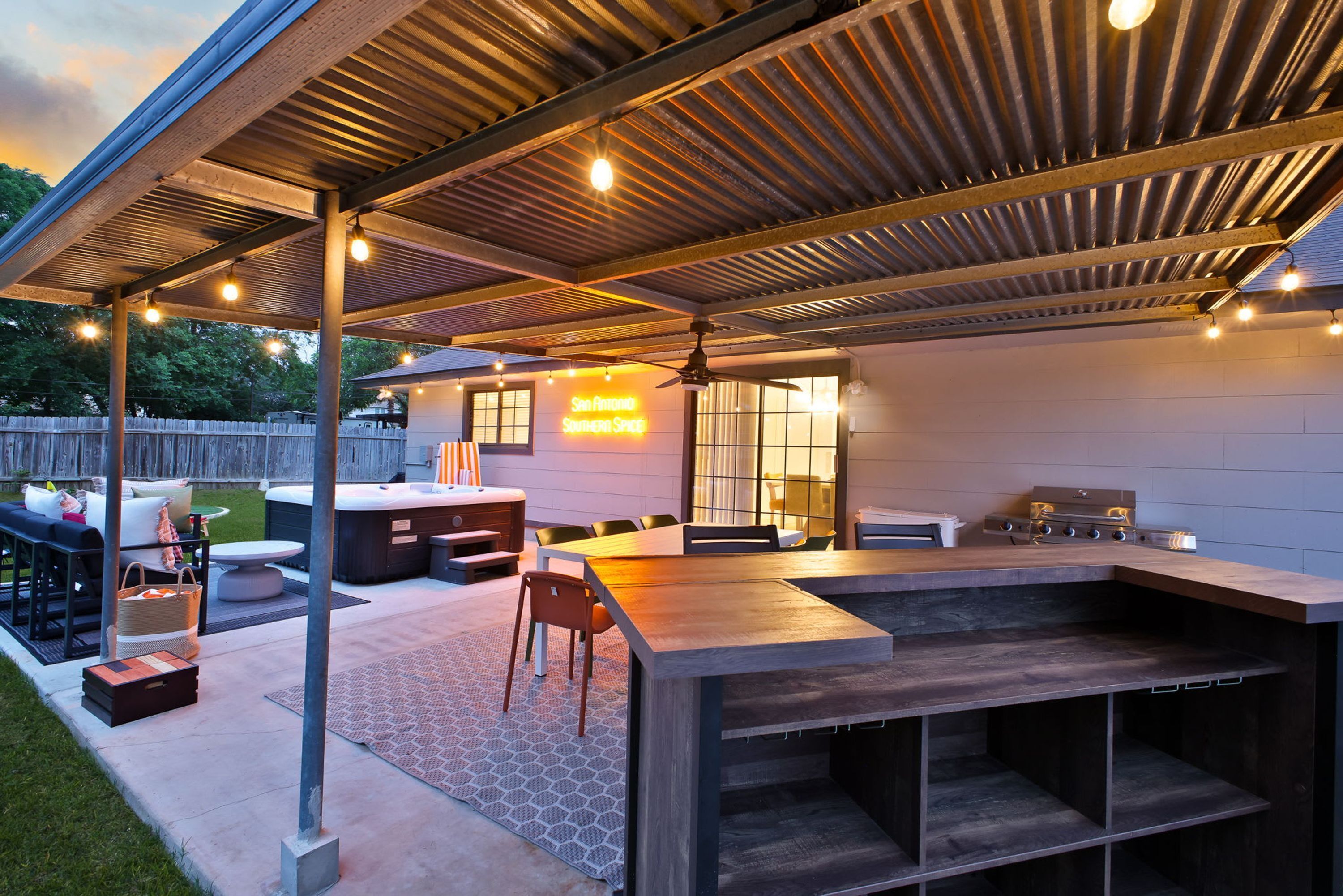 Een terras buiten met een bar, zitplaatsen en een jacuzzi.