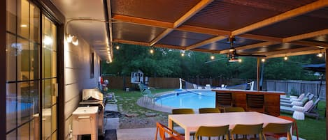 Une terrasse extérieure avec une piscine, un espace barbecue et un coin salon abrité.