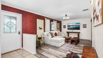 A living room with a white sofa, a coffee table, a television, and a fireplace.