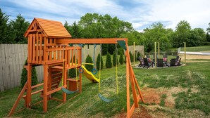 A wooden play structure with a slide and swing set in a backyard. - 7 Br Sleeps 20 Sport Court Pool Hot Tub Playground (Arden)