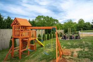 A wooden play structure with a slide and swing set in a backyard. - 7 Br Sleeps 20 Sport Court Pool Hot Tub Playground (Arden)