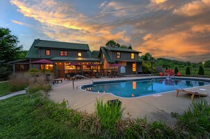 A two-story building with a swimming pool, outdoor seating, and a covered patio area.
