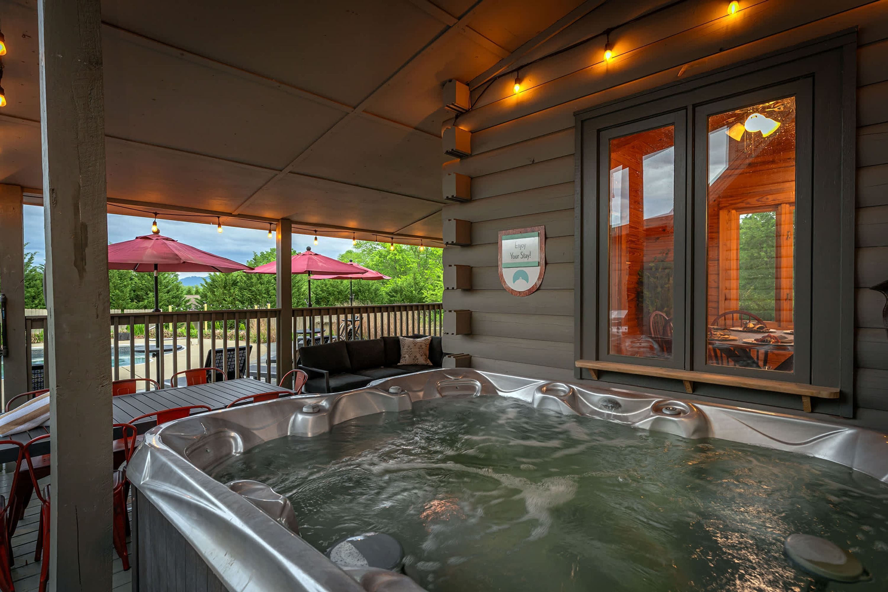 A hot tub area with a view of a pool and outdoor seating.