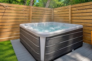 Ein Whirlpool mit einer Holzterrasse und einem Holzzaun im Hintergrund.