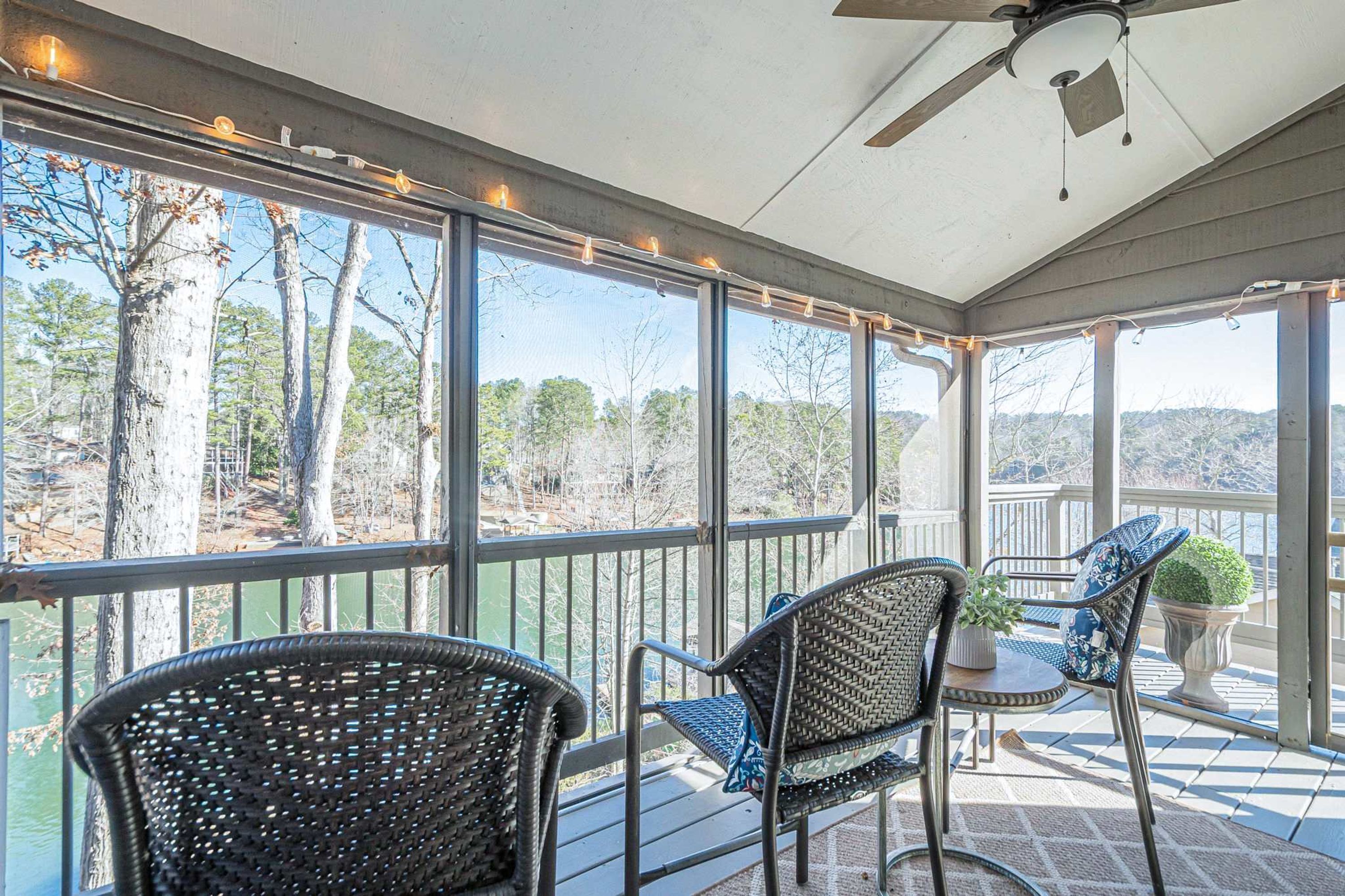 A covered outdoor area with wicker chairs, a small table, and a ceiling fan.