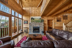 Un intérieur en bois agrémenté d’une cheminée en pierre, de meubles en cuir et de grandes fenêtres.