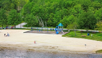 A sandy beach area with a playground and picnic tables.
