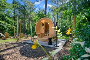 A wooden cabin with a circular entrance, surrounded by a forest. - Sleeps 6 Sauna Hot Tub Putt Putt Dogs Welcome (Broken Bow)