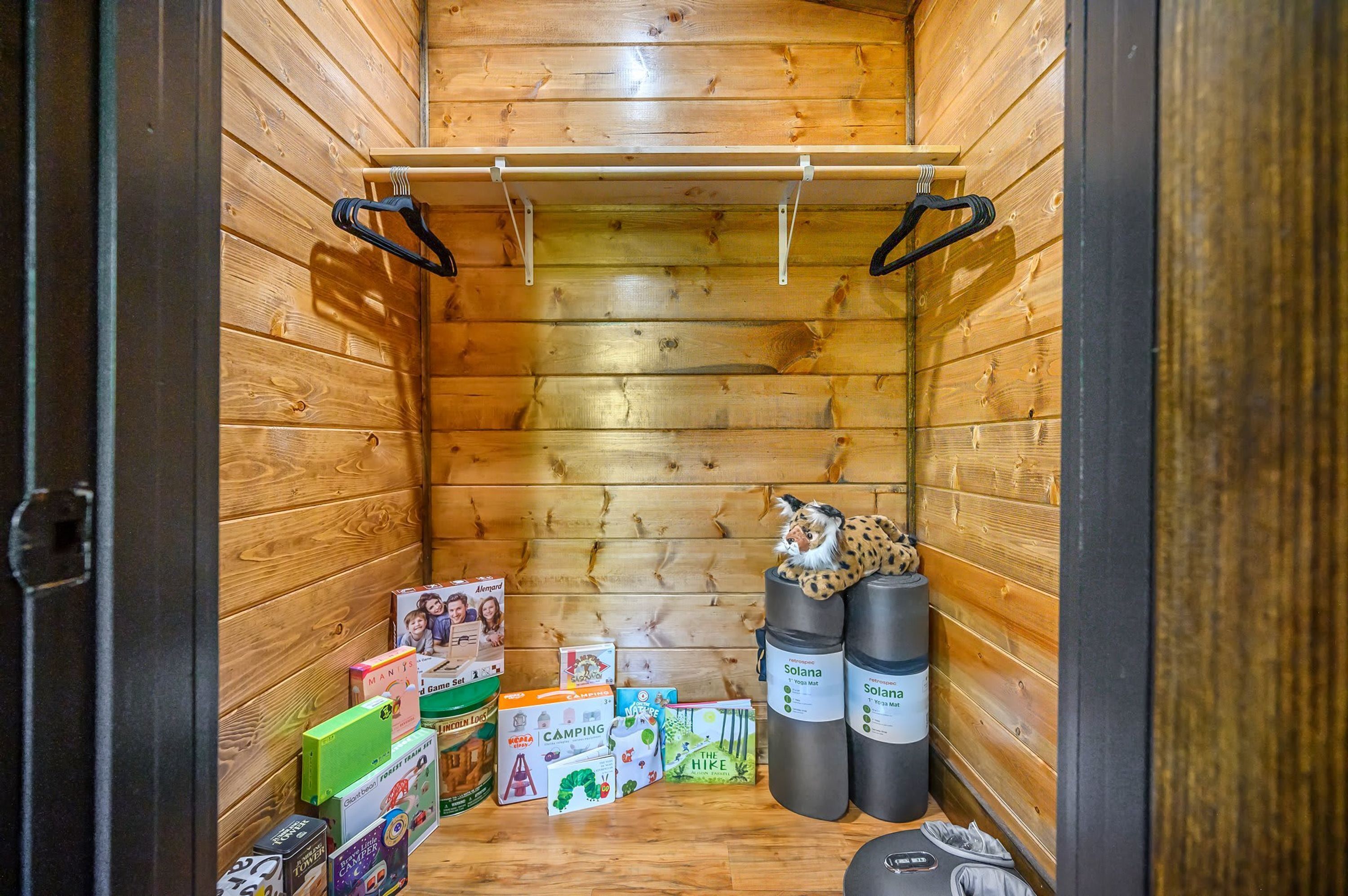 Innenansicht einer Holzhütte mit Schlafkoje, Kleiderstange und verschiedenen Spielsachen und Spielen für Kinder.