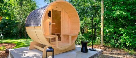 Una struttura cilindrica in legno con una panca all'interno, un tavolino e una lanterna a terra.