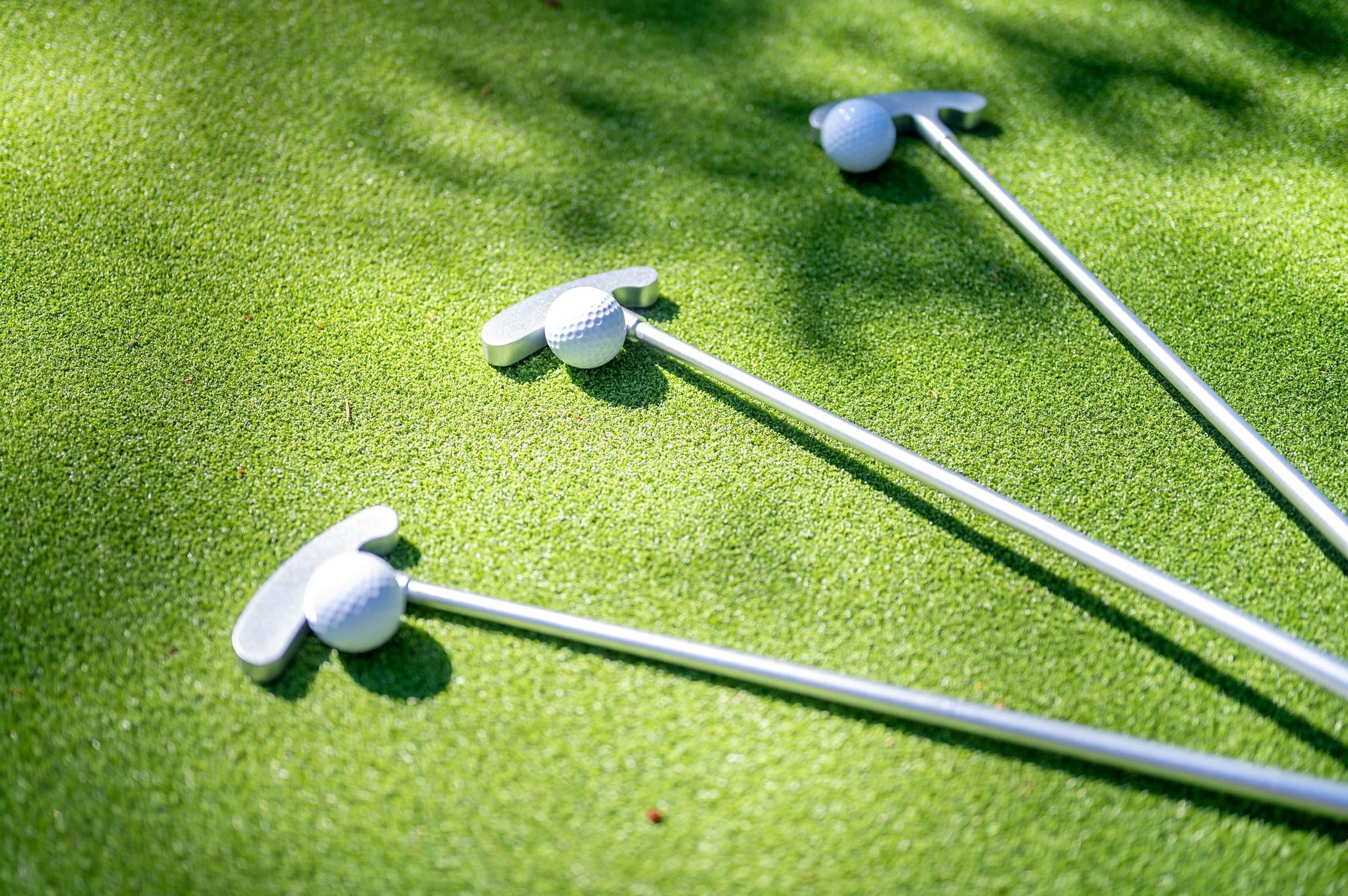 Tres palos de golf sobre un césped.