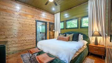 Un dormitorio con cama, dos sillas, una mesita de noche, lámpara y ventilador de techo.