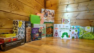 Uma variedade de jogos de tabuleiro infantis e livros dispostos sobre um piso de madeira.