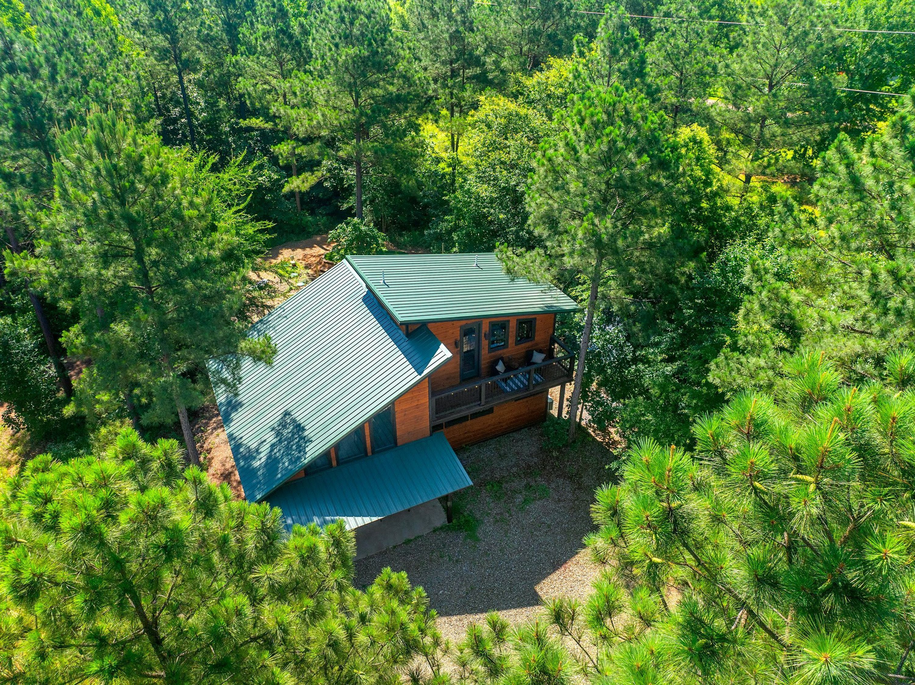 Una cabaña rodeada de un bosque denso, con techo inclinado y un área de terraza.