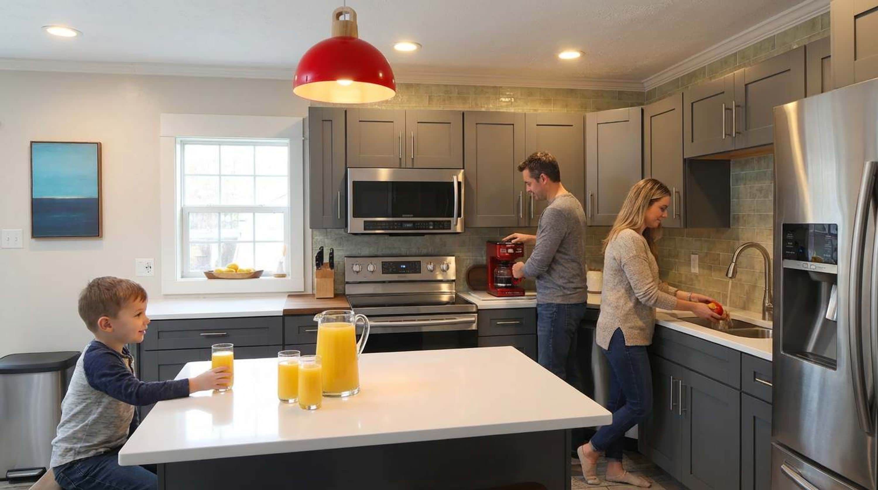 A modern kitchen with stainless steel appliances, a central island, and a red pendant light.