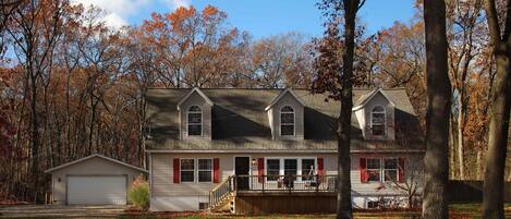 A two-story house with a garage, a front porch, and a small shed.