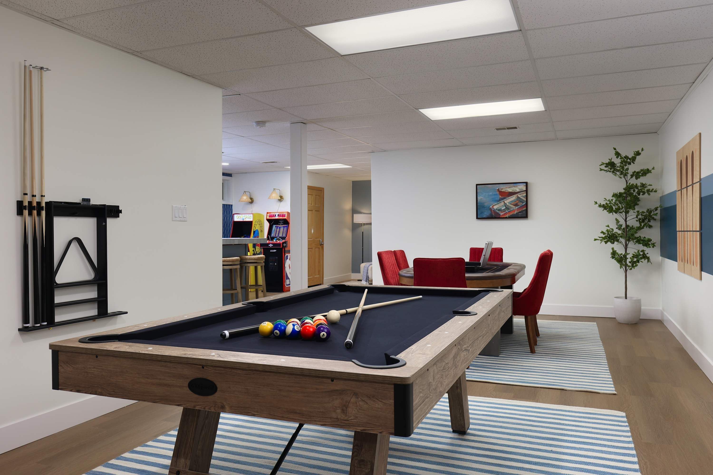 A pool table with balls, a billiard rack, and a nearby seating area with a table and chairs.