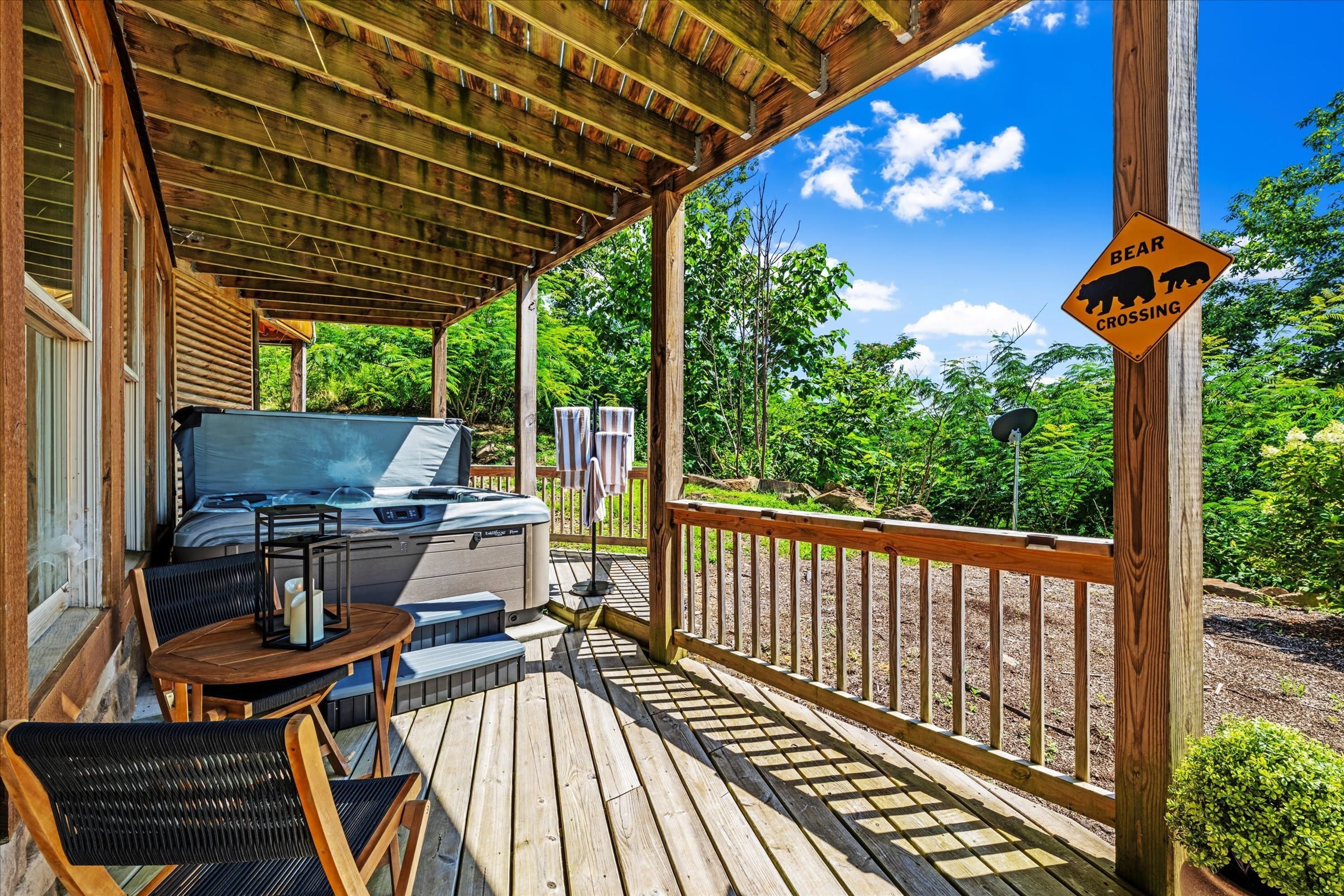 A covered outdoor deck with a barbecue grill, chairs, and a bear crossing sign.