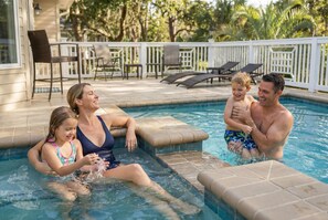 A swimming pool with a tiled deck, lounge chairs, and a white fence. - Coastal Luxe Retreat - Heated Pool - Games - Games (Hilton Head Island)