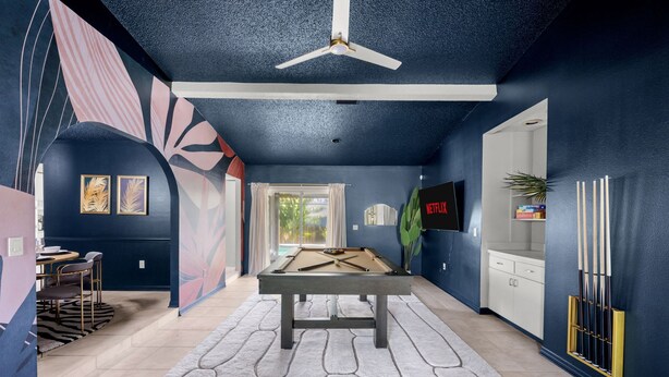 Ein Zimmer mit Billardtisch, Deckenventilator und Wandfernseher.