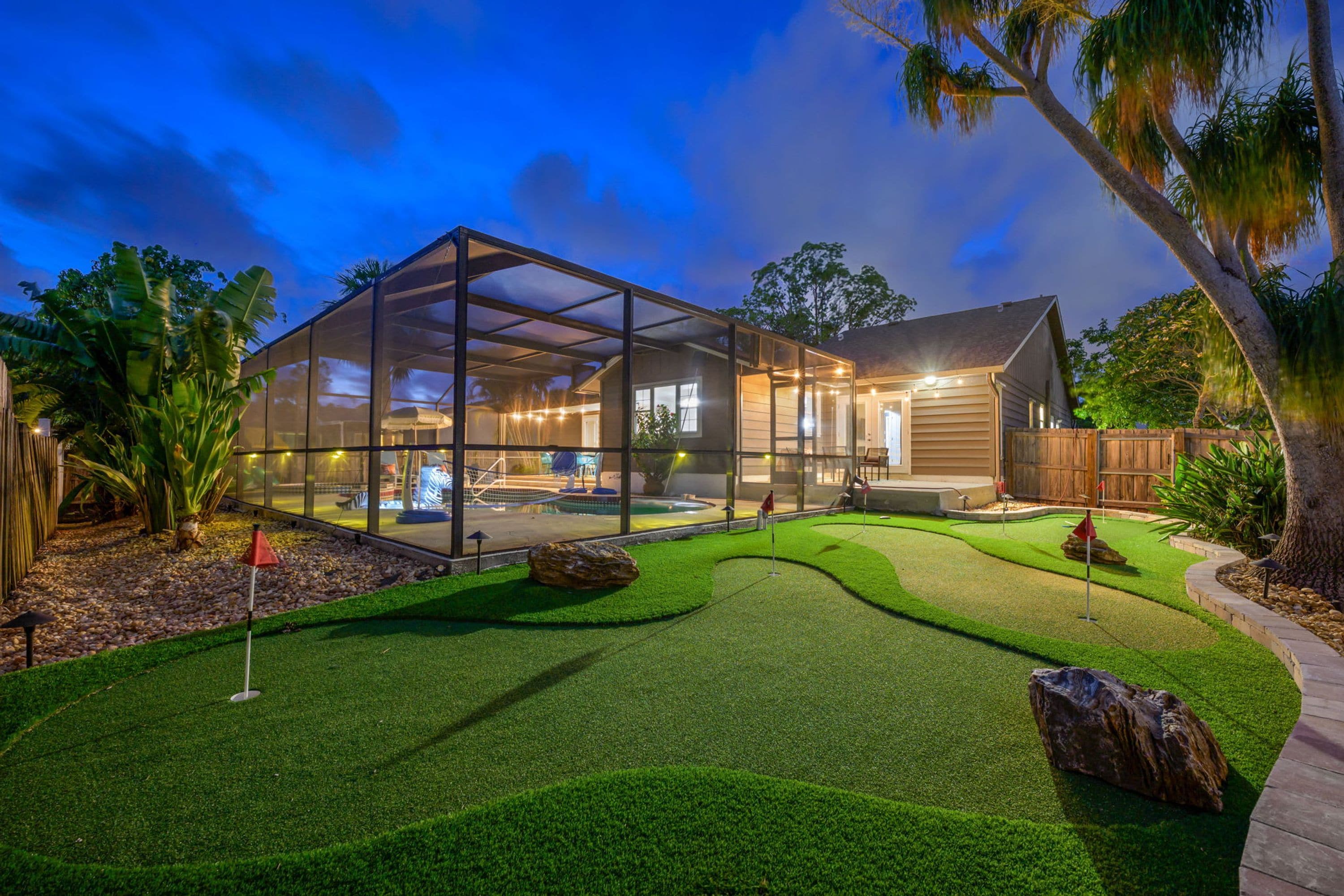 Une maison moderne dotée d’un patio entièrement vitré, d’une piscine et d’une pelouse bien entretenue.