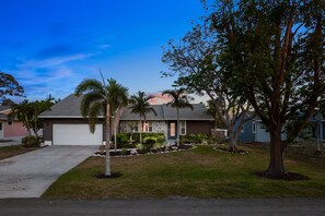 A residential house with a garage, a well-maintained lawn, and a variety of trees. - Family Retreat Pool Putt Putt Playground (Bradenton)