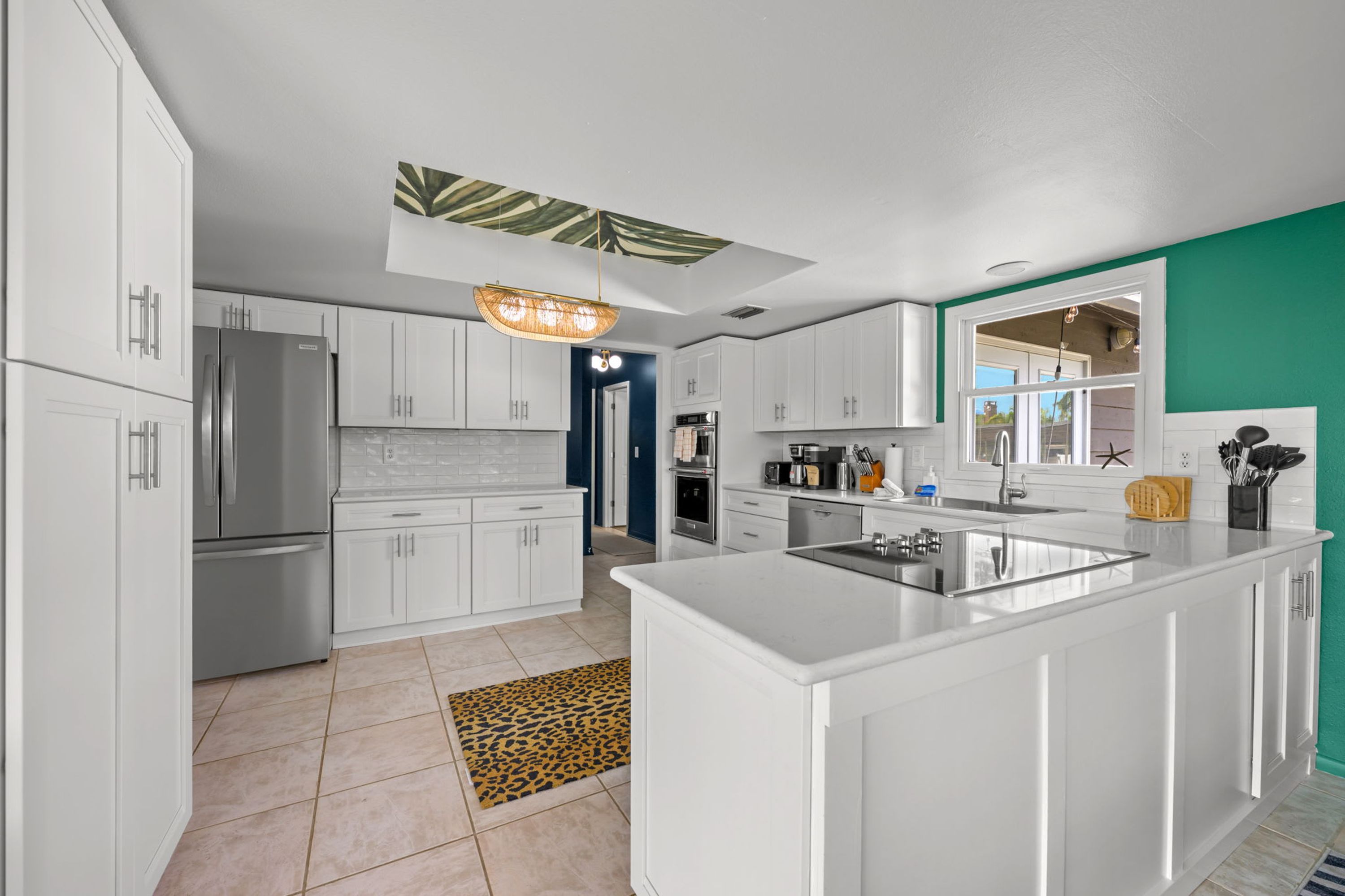 A modern kitchen with white cabinetry, a central island, and a unique ceiling design.