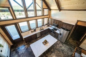 A spacious kitchen with large windows, a central island, and modern appliances. - Sleeps 13 Hot Tub Arcade Firepit Games (Broken Bow)