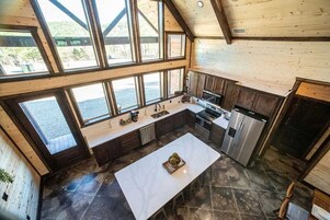 Una cocina amplia con ventanas grandes, una isla central y electrodomésticos modernos.