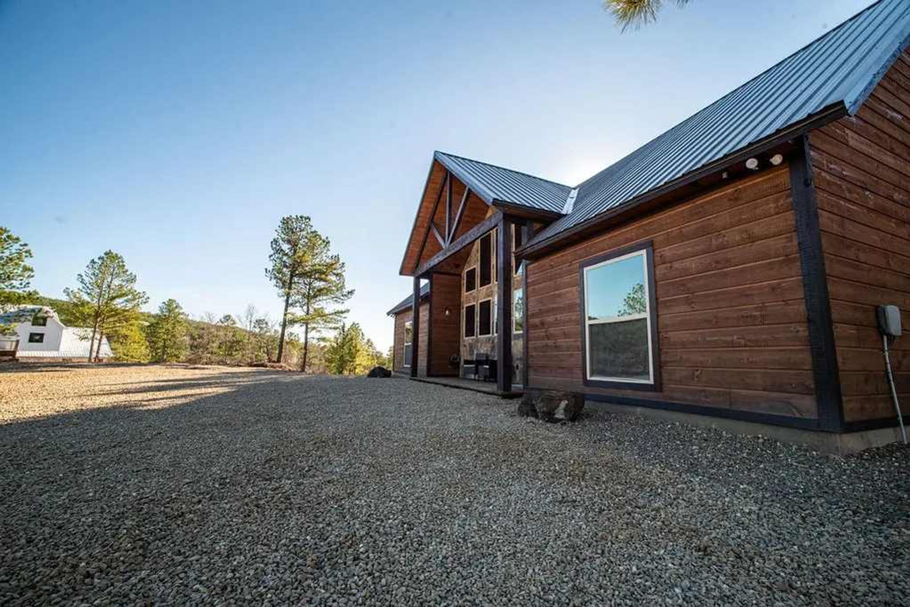 A wooden cabin with a gravel driveway and a metal roof.