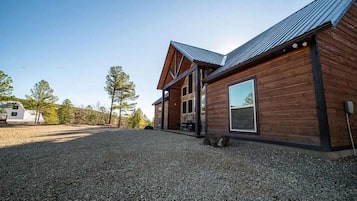 A wooden cabin with a gravel driveway and a metal roof.