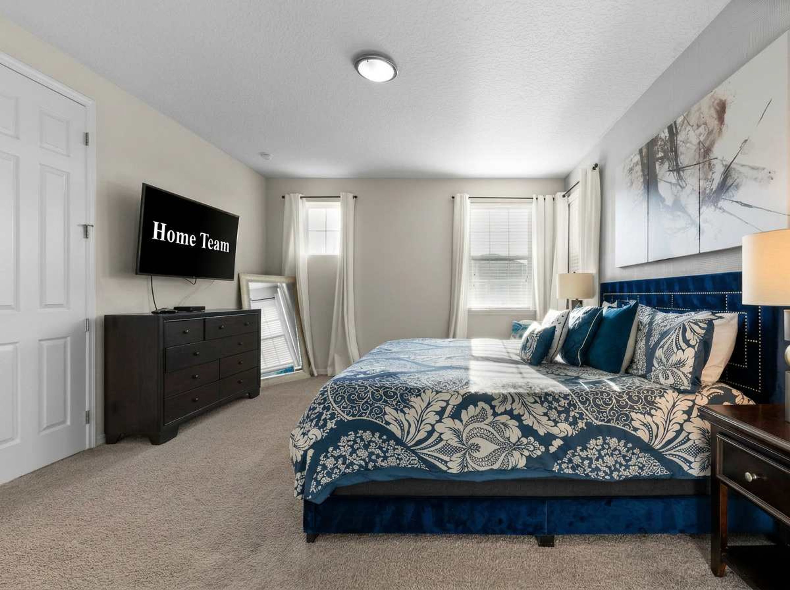 A bedroom with a bed, a dresser, a television, and a window with curtains.