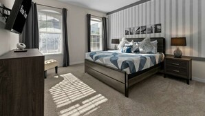A bedroom with a bed, bedside tables, a TV, and a window with curtains. - 6 Mins to Disney Game Themed Rooms Pool Spa (Kissimmee)