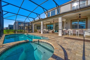 Piscina com cobertura de vidro, área de estar ao ar livre e um terraço com mesas e cadeiras.