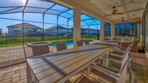A covered outdoor patio with a pool, seating, and a view of houses in the background. - 6 Mins to Disney Game Themed Rooms Pool Spa (Kissimmee)