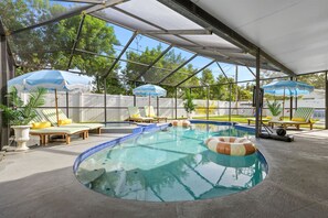 An indoor swimming pool with a glass ceiling, surrounded by lounge chairs and umbrellas. - Private Pool Movie Theater Putting Playground (Seminole)