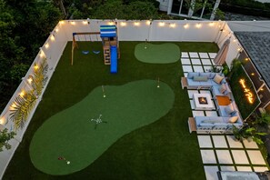 Um quintal com área de recreação infantil, área de estar com lareira e uma piscina pequena.