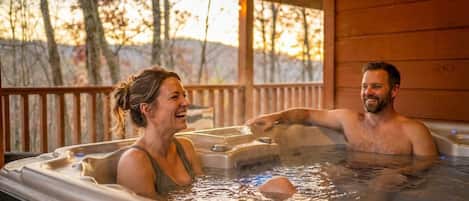 Una cabaña de madera con jacuzzi y vista a árboles.