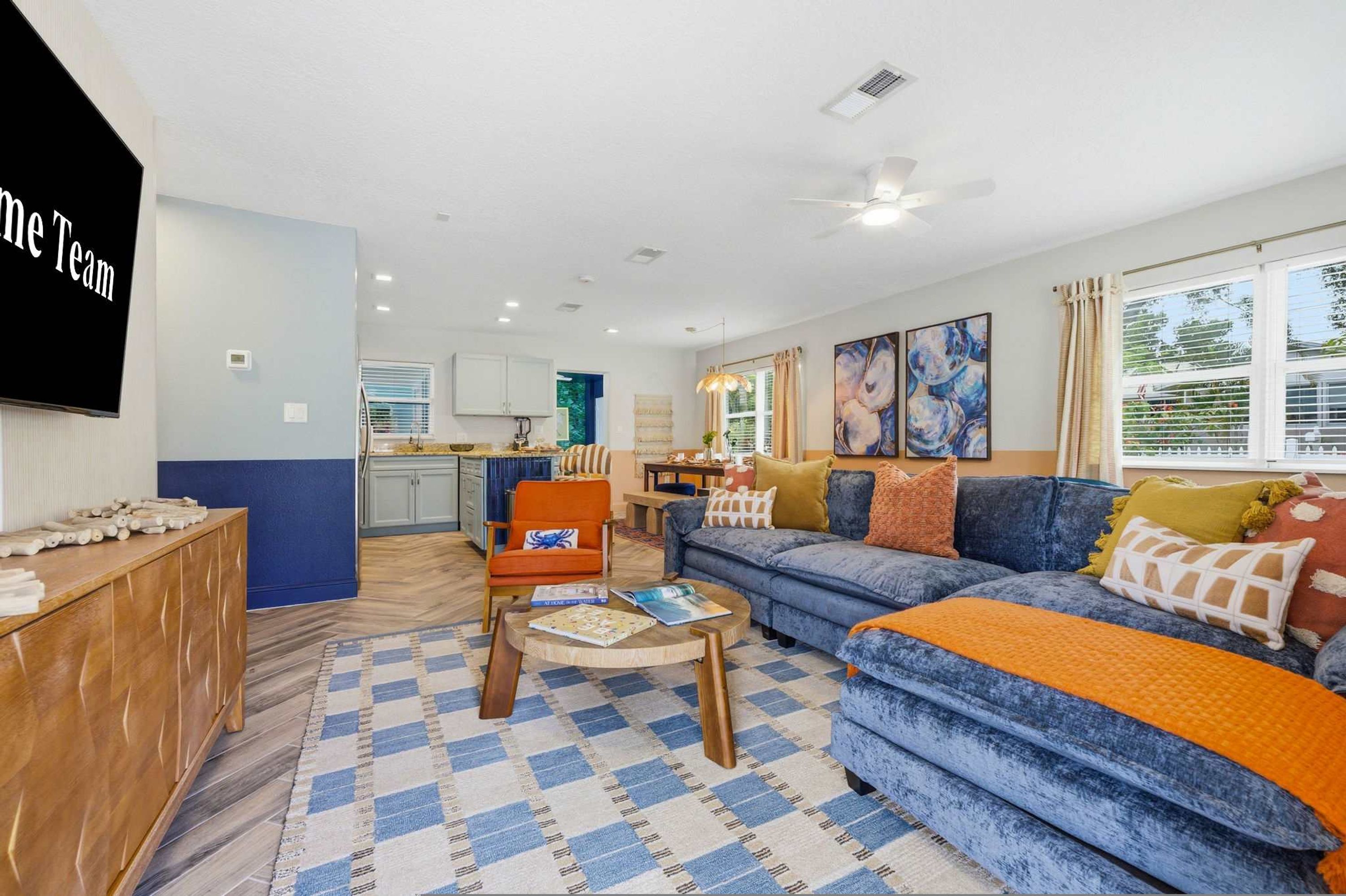 A living room with a sofa, armchairs, a coffee table, and a TV mounted on the wall.